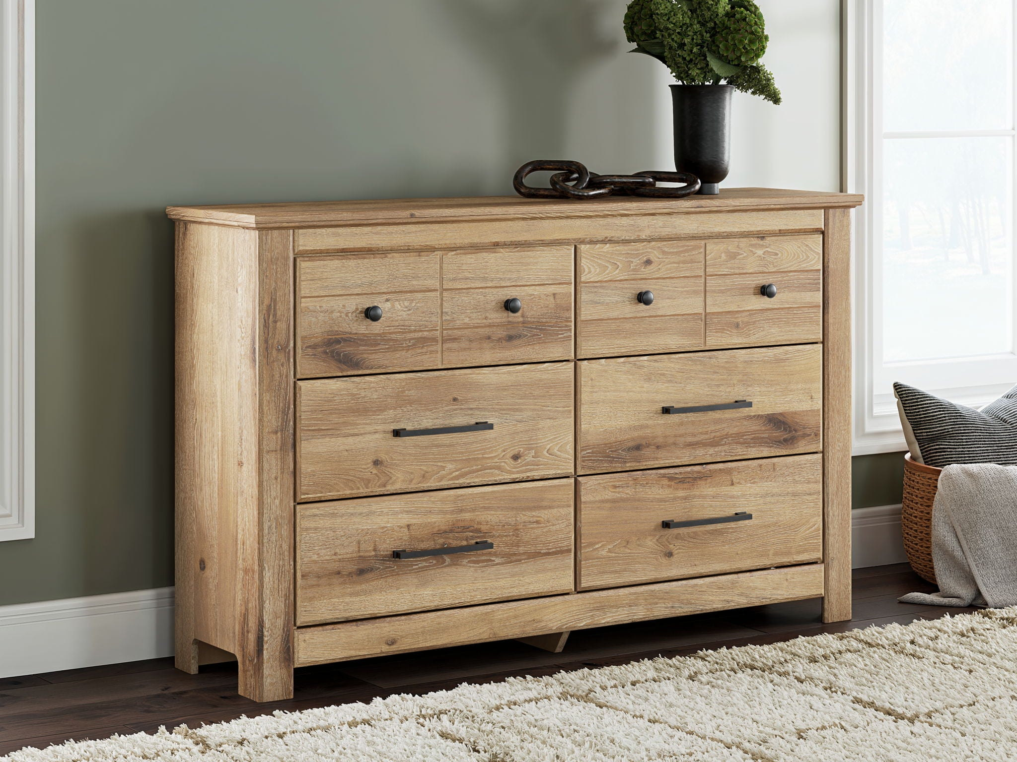 Light brown six-drawer dresser with black knobs and bar pulls, wide front view