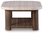 Rectangular cocktail table with light beige tabletop and dark woven lower shelf