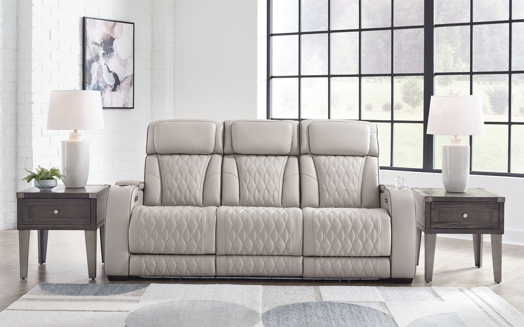 Gray power reclining sofa with quilted upholstery and three padded headrests