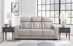 Gray power reclining sofa with quilted upholstery and three padded headrests