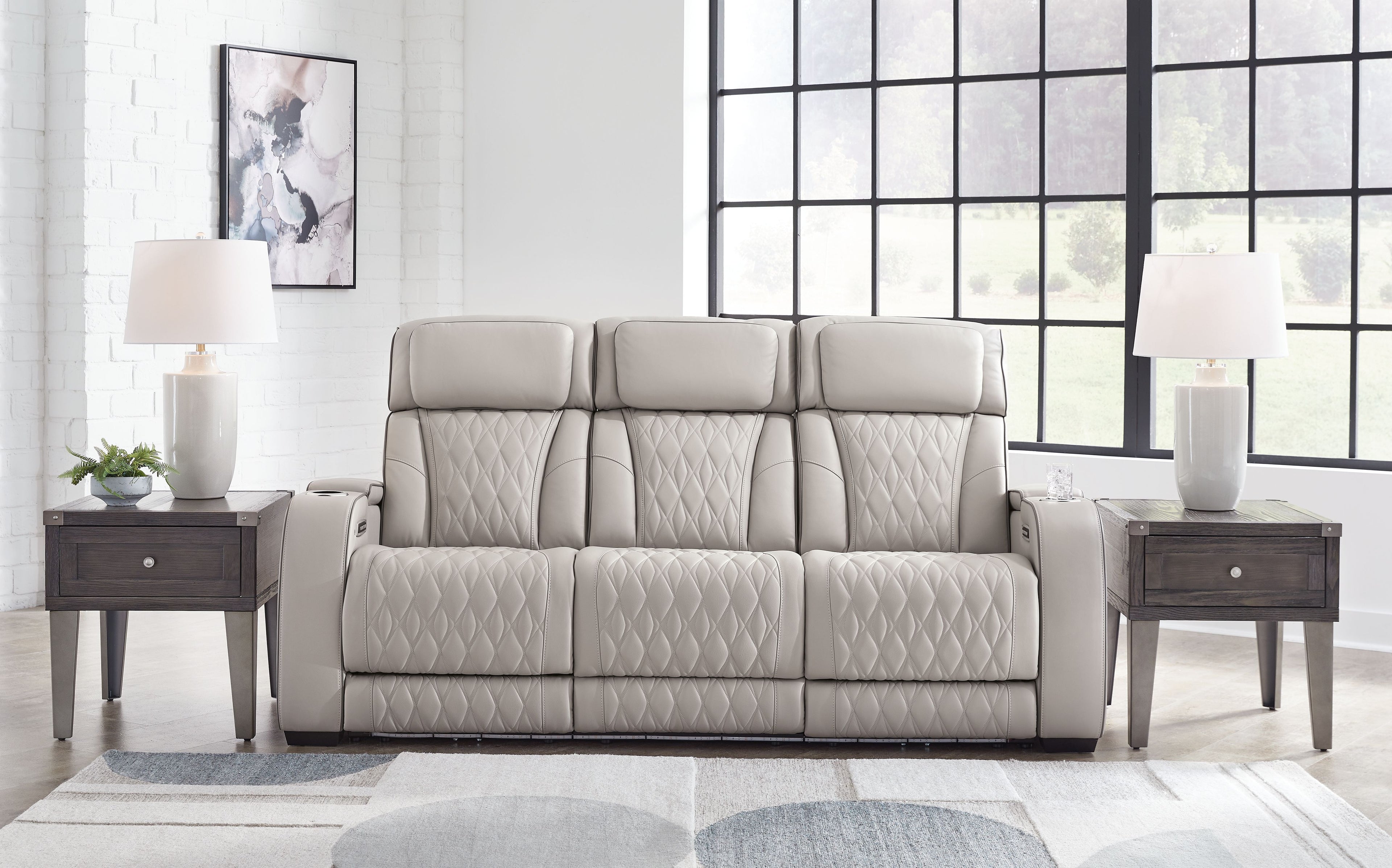 Gray power reclining sofa with quilted upholstery and three padded headrests