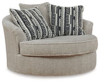 Light beige oversized swivel accent chair with round ottoman seat and patterned throw pillows