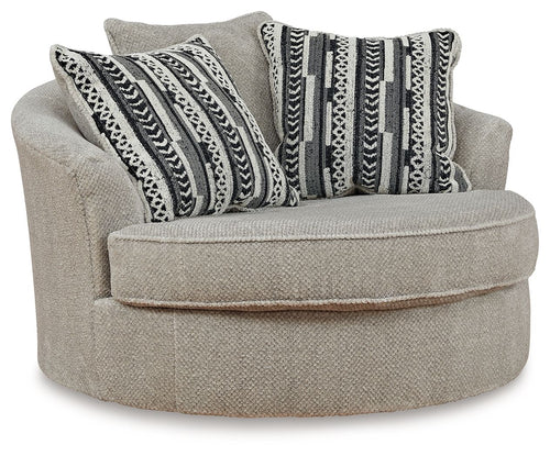 Light beige oversized swivel accent chair with round ottoman seat and patterned throw pillows
