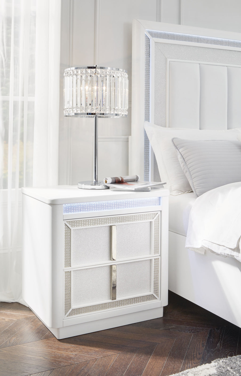 White two-drawer nightstand with mesh cabinet fronts beside a bed.