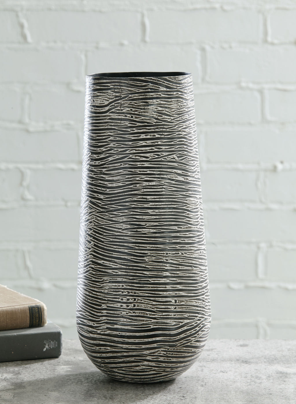 Tall ceramic vase in dark gray with light wave-etched lines, cylindrical silhouette.