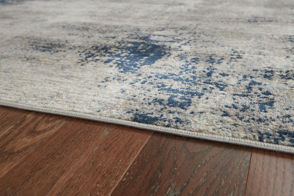 Close-up of gray rug with blue mottled design and low-profile edge binding