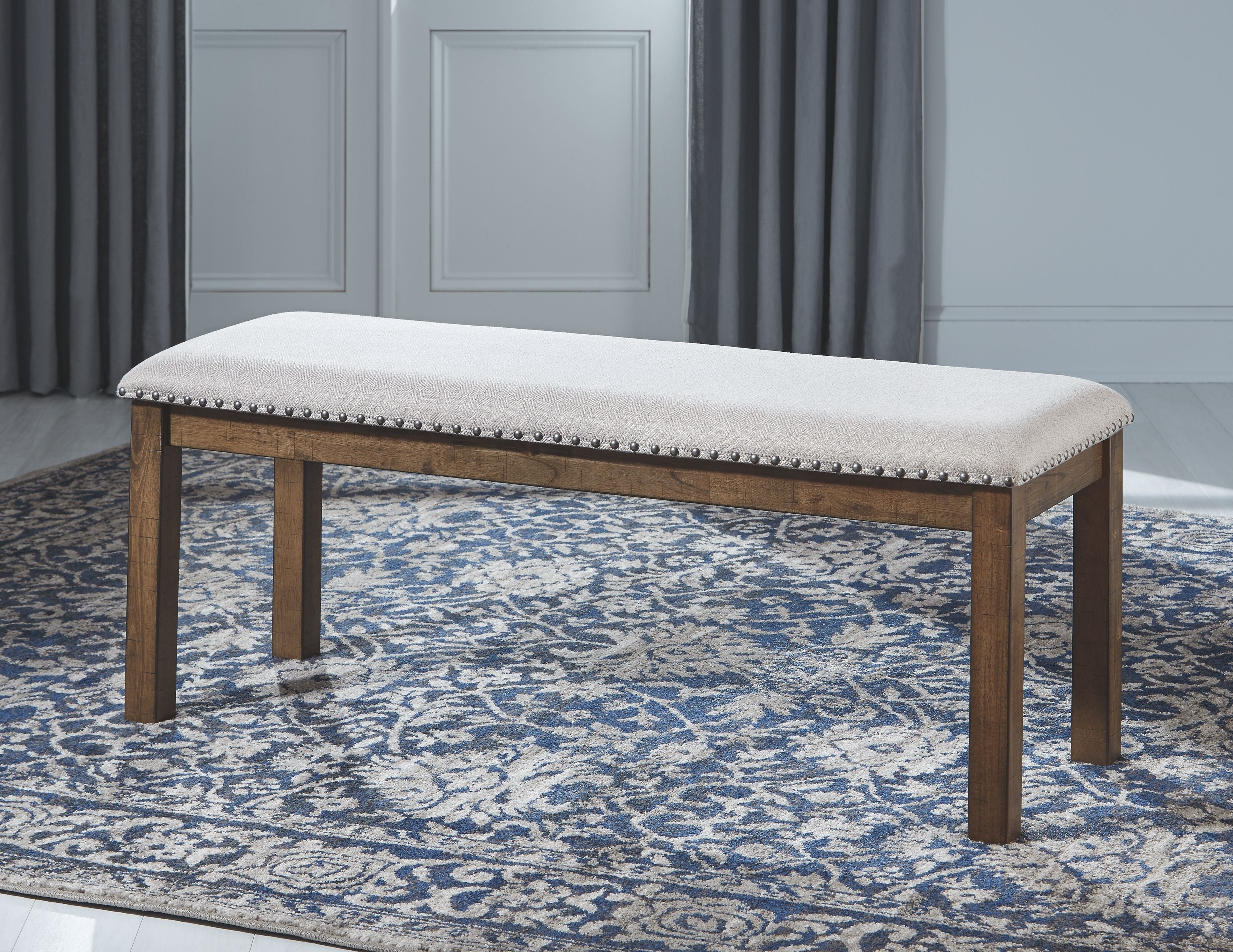 Upholstered dining bench with dark wood frame, nailhead trim, light seat cushion