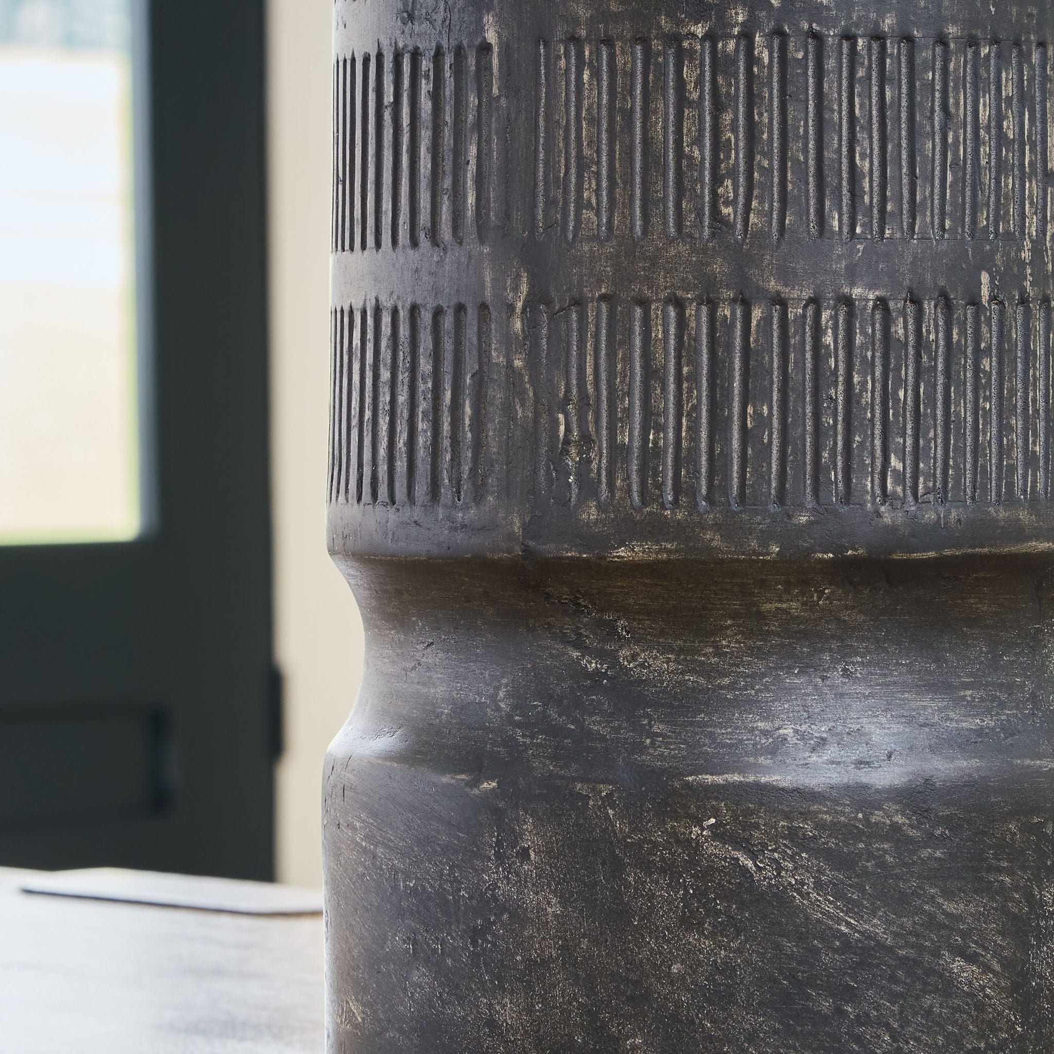 Beninworth vase close-up, black ribbed surface and worn pedestal base detail.