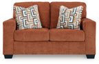 Rust orange loveseat with two patterned throw pillows on the back cushions.