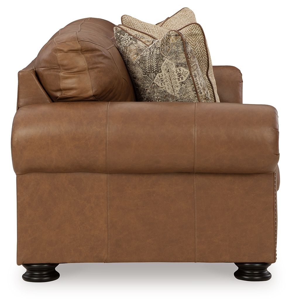 Brown upholstered armchair with rolled arms and multiple patterned throw pillows