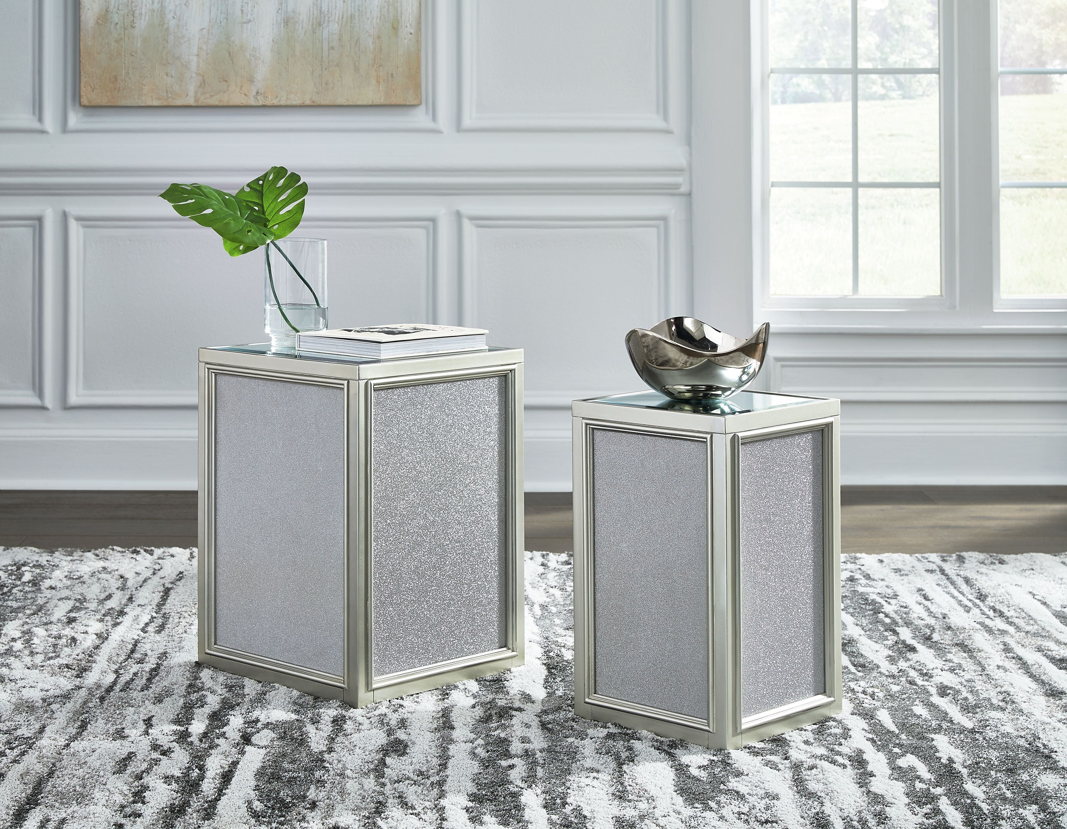 Set of 2 silver nesting end tables with textured sides and glass tops, standing together