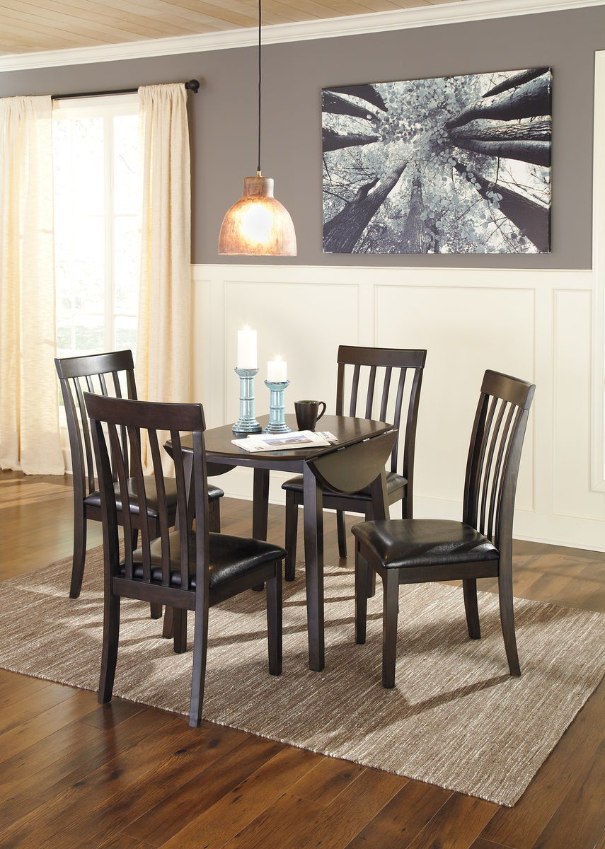 Dark brown round dining table set with four slat-back chairs and black padded seats