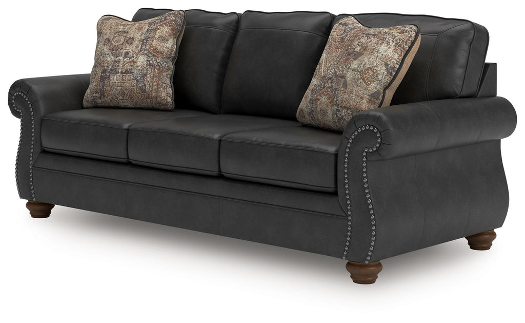 Chasemore sofa in dark gray with two patterned pillows and nailhead trim