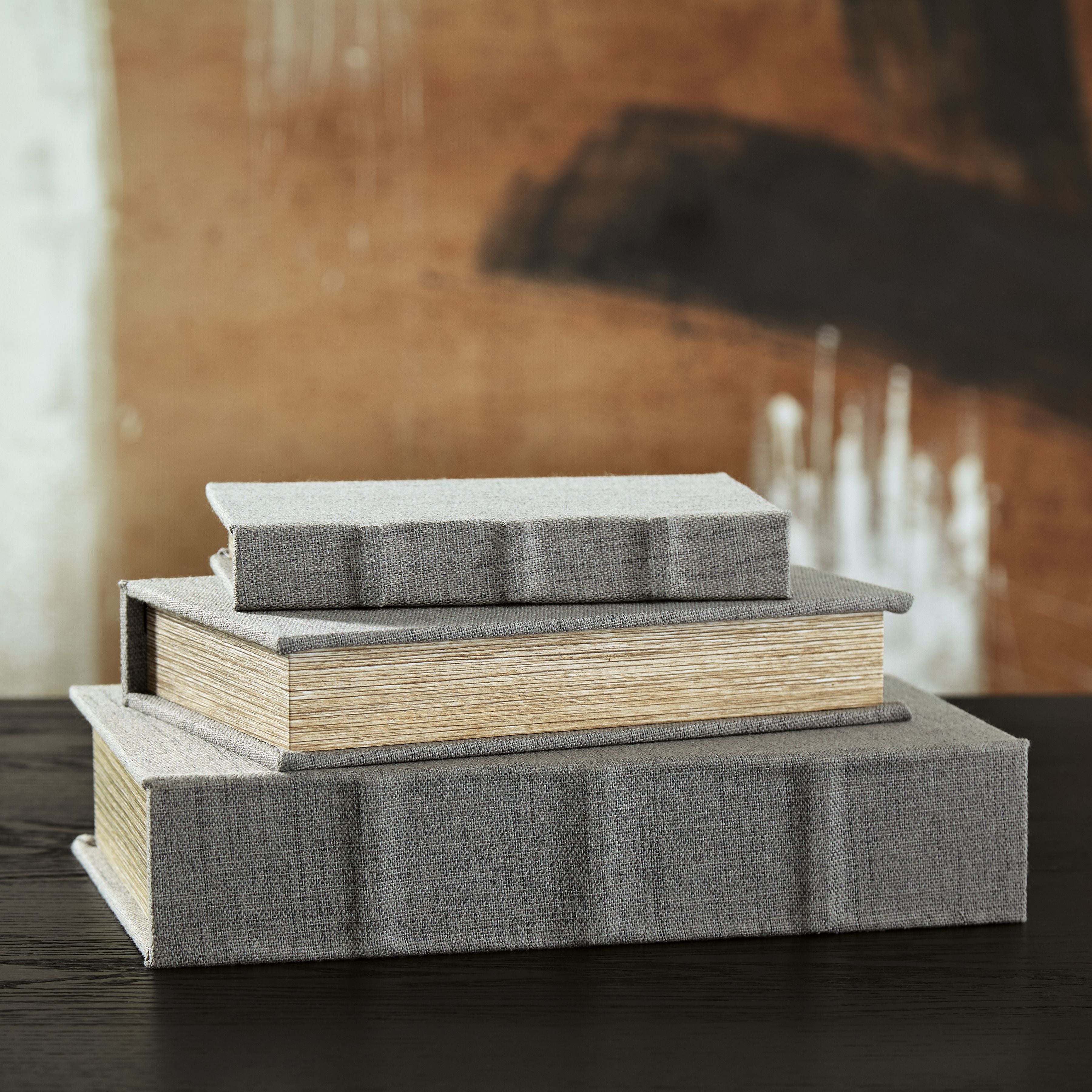 Decorative box set with stacked gray fabric lids on wood-textured boxes.