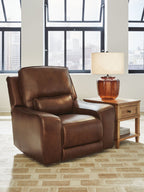 Caramel power recliner chair with adjustable headrest and padded armrests, side view.