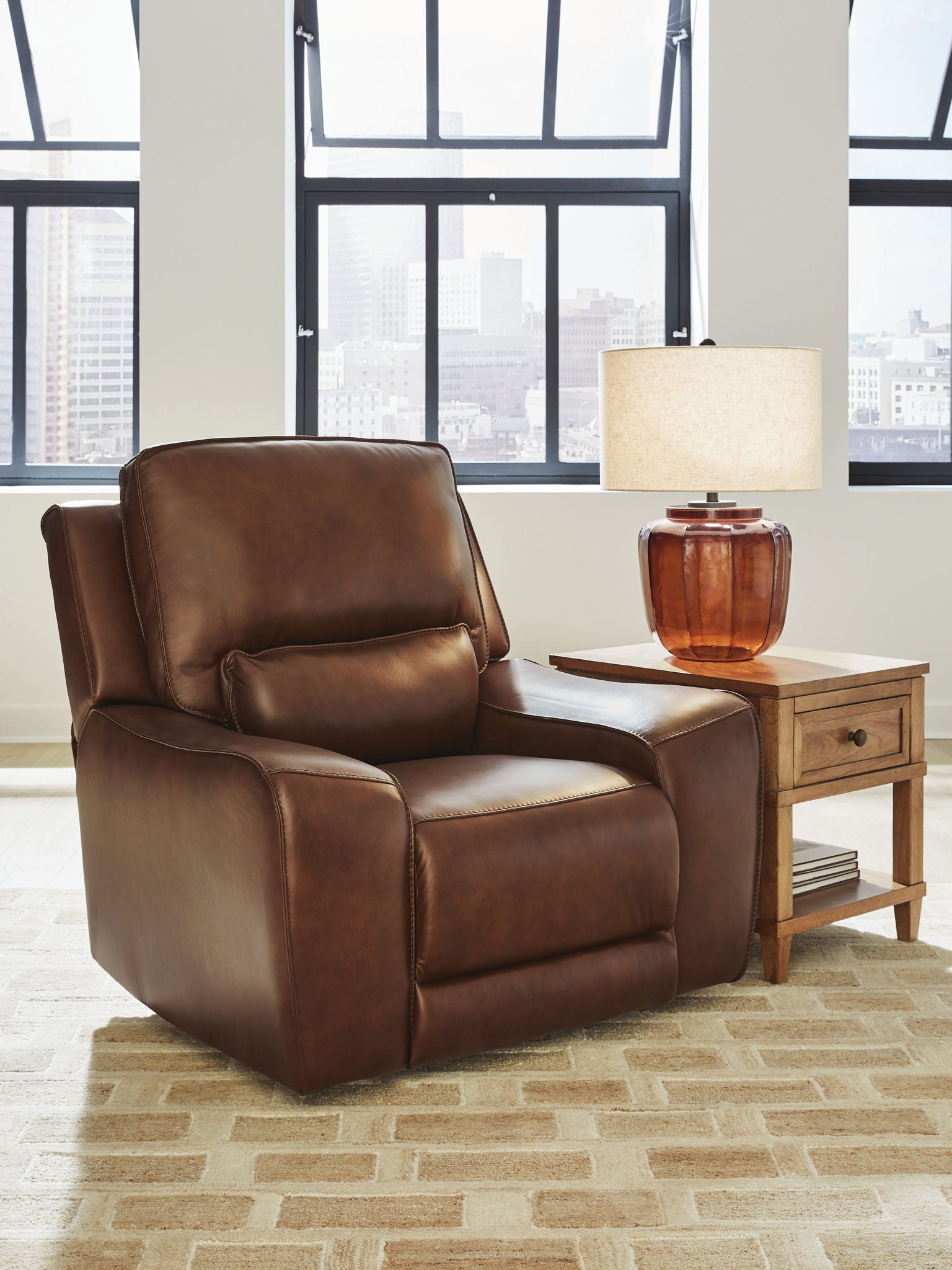 Caramel power recliner chair with adjustable headrest and padded armrests, side view.