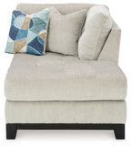 Stone corner chaise with tufted back, dark legs, and geometric throw pillow