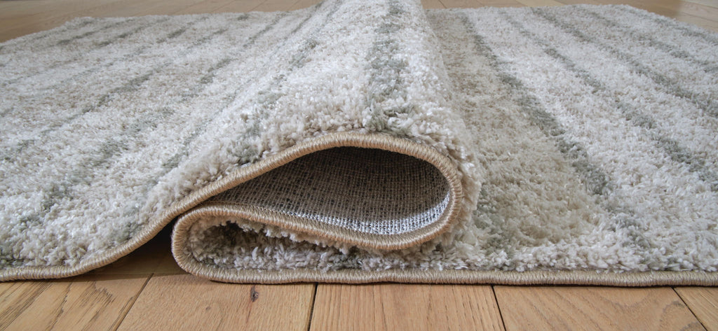 Cream and green rug corner with stitched border and visible underside backing