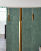 Gold metal lamp pole with two dangling pull cords and a textured shade backdrop.