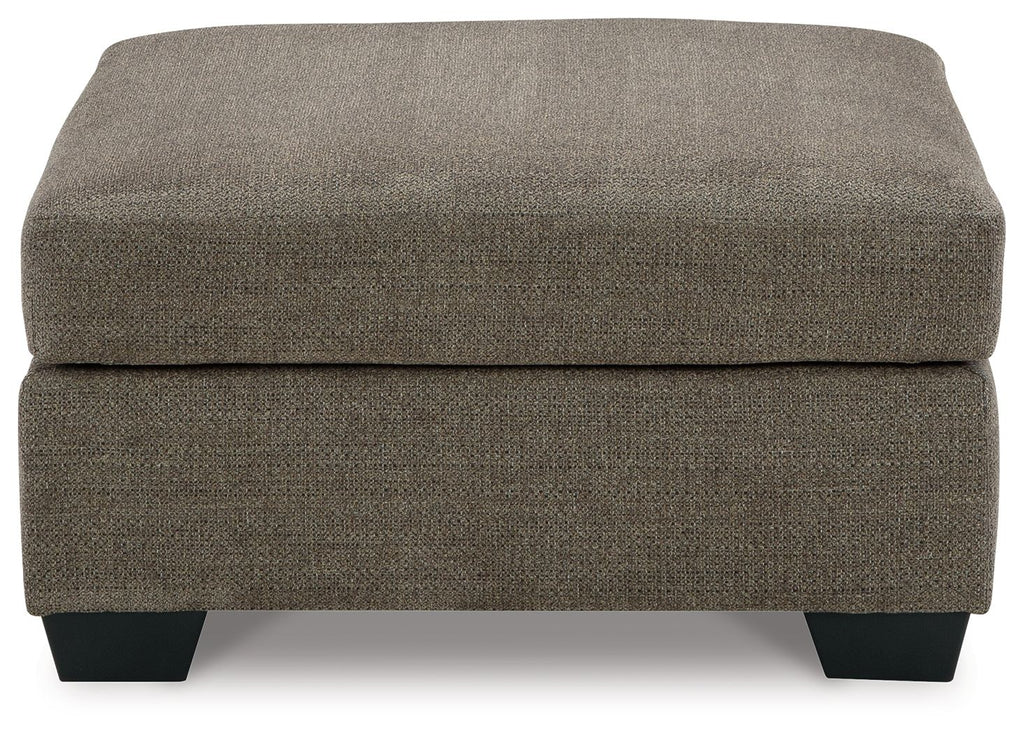 Oversized ottoman with dark brown fabric, thick cushioned top and squared black legs.