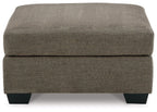 Oversized ottoman with dark brown fabric, thick cushioned top and squared black legs.