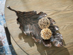 Antique copper leaf-shaped sculpture tray on wood with twine ball and beige flower