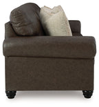 Dark brown sofa chaise section with thick arm and two beige pillows