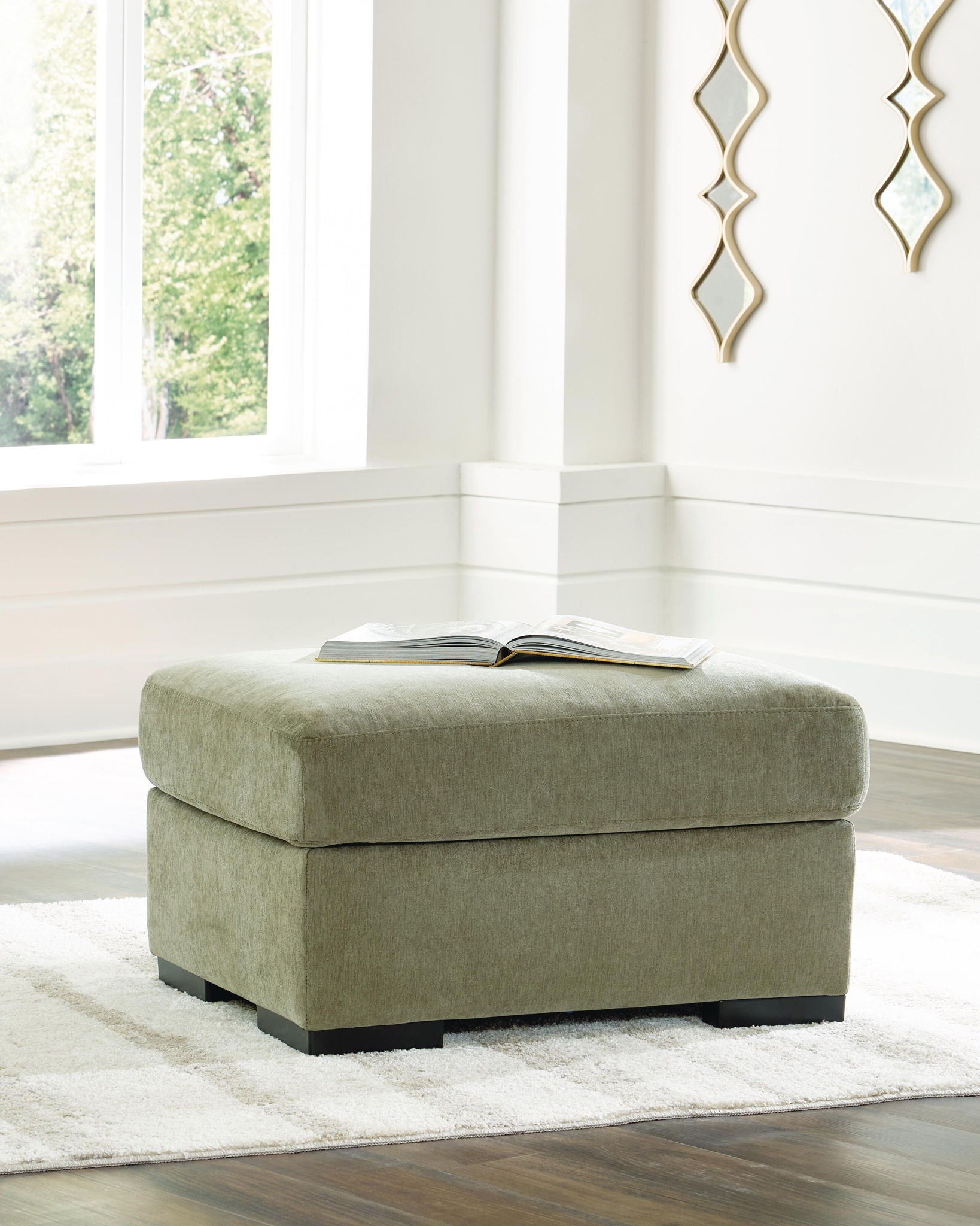 Green upholstered ottoman with square padded seat and black legs
