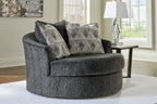 Dark gray upholstered swivel accent chair with two geometric throw pillows