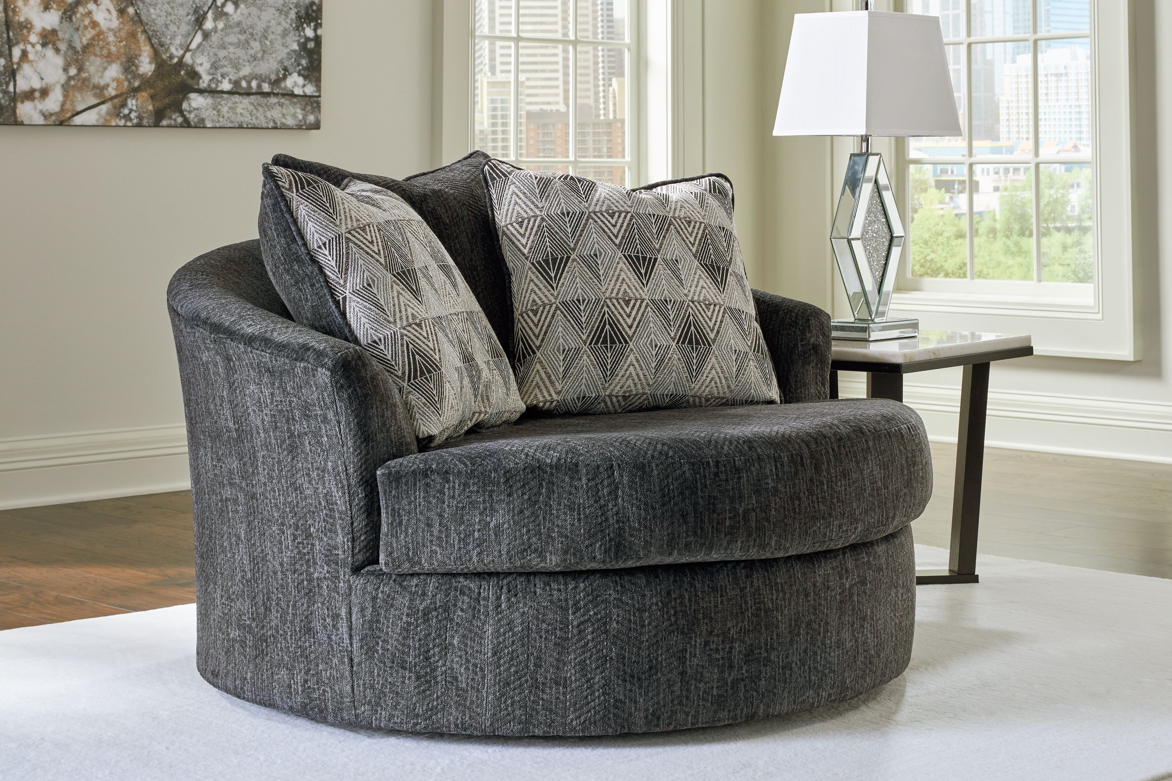 Dark gray upholstered swivel accent chair with two geometric throw pillows