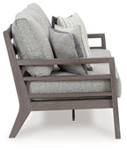 Gray outdoor sofa chair-style with cushions and stacked throw pillows