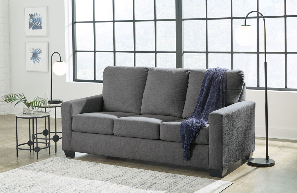 Dark gray sofa with cushioned back and armrests, styled with a blue throw blanket