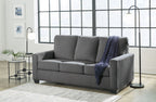 Dark gray sofa with cushioned back and armrests, styled with a blue throw blanket