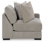 Light gray corner armchair with rounded arm, dark feet, and two throw pillows