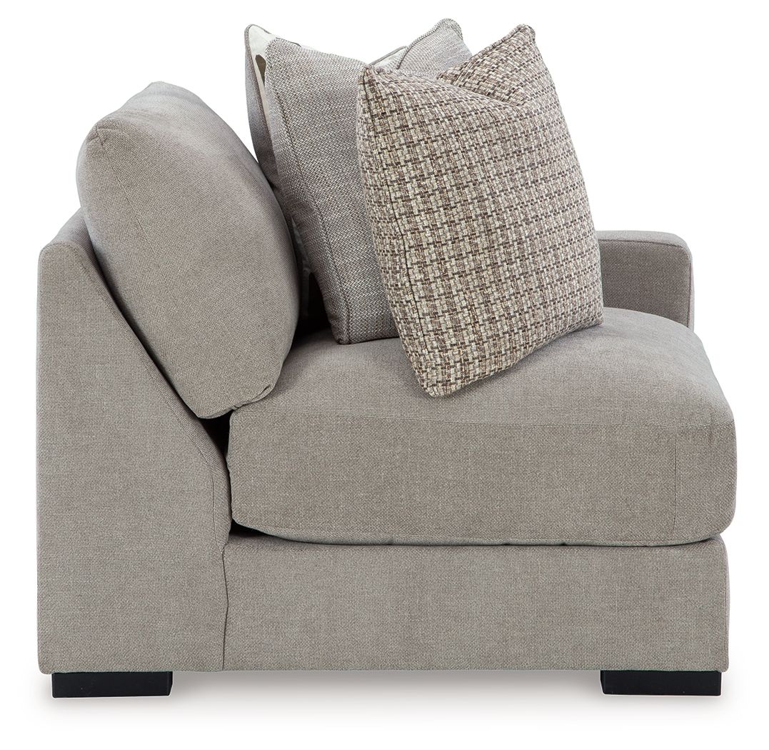 Light gray corner armchair with rounded arm, dark feet, and two throw pillows