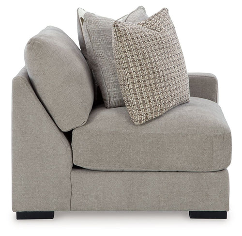 Light gray corner armchair with rounded arm, dark feet, and two throw pillows
