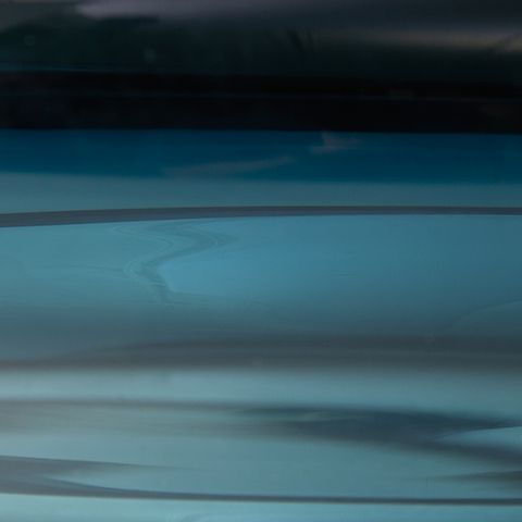 Teal blue glass bowl close-up, glossy surface and rim detail