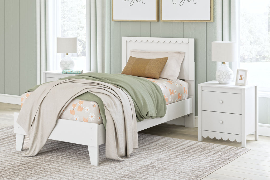 White panel platform bed with scalloped headboard, layered bedding and decorative pillows