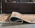 Rolled brown and tan geometric area rug showing textured pile and curved edge.