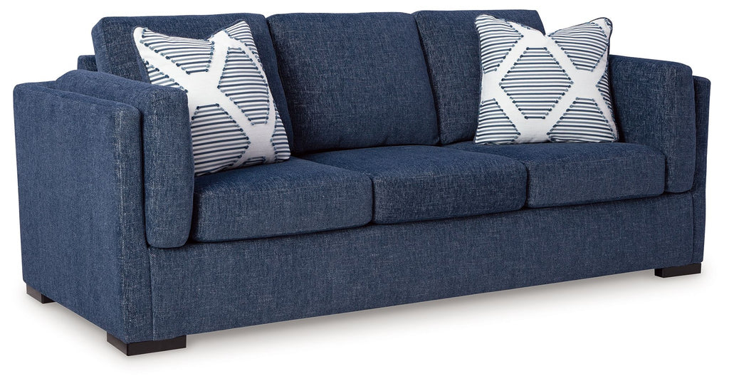Blue upholstered sofa with three seat cushions and two striped pillows