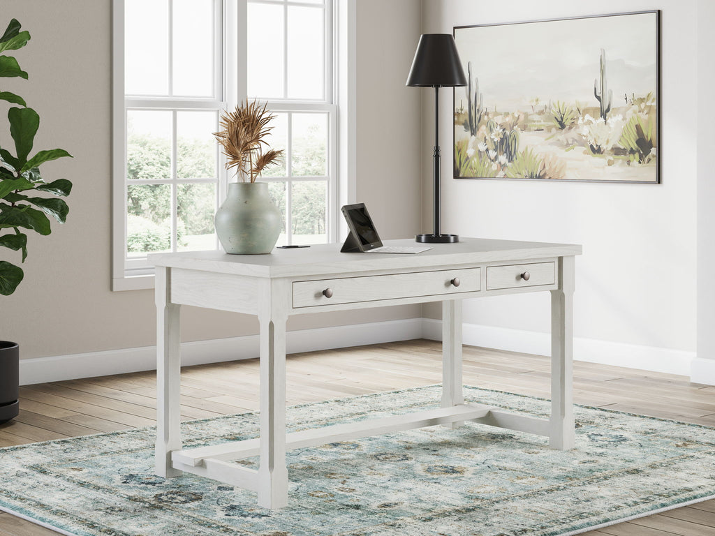 White home office desk set with drawers, lamp, and framed wall art in the room