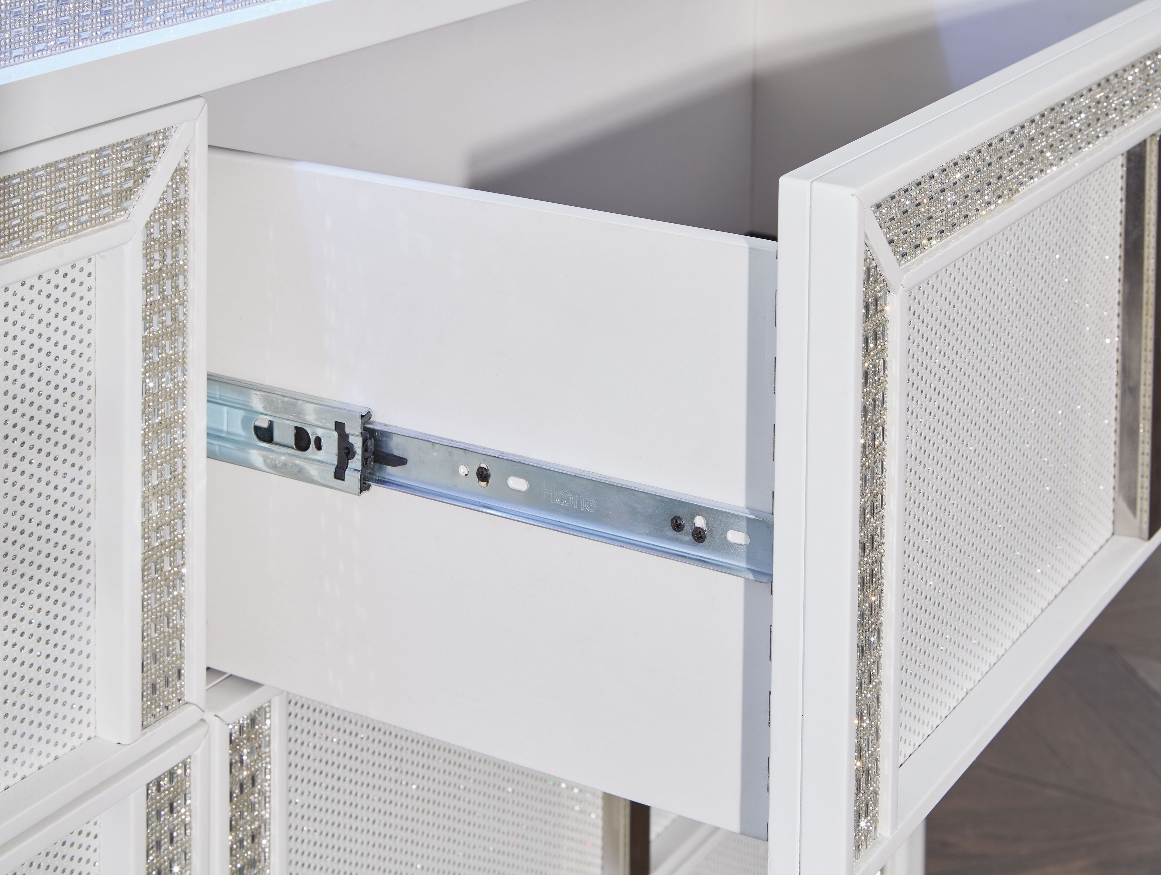 White dresser interior with metal rail and push-catch hardware