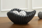 Black fluted bowl holding two white grid-pattern balls