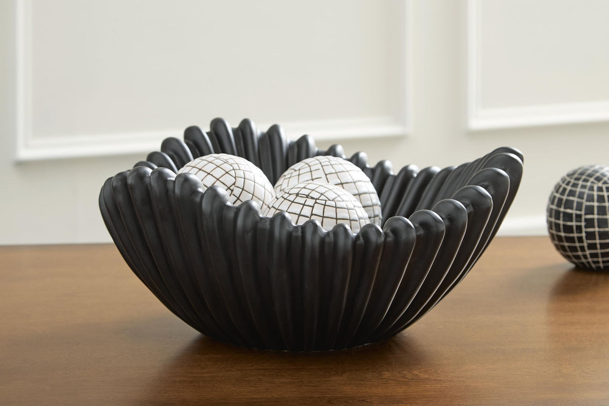 Black fluted bowl holding two white grid-pattern balls