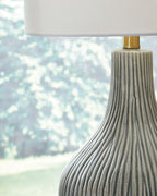 Gray ceramic lamp base with vertical ridges and gold collar under white shade