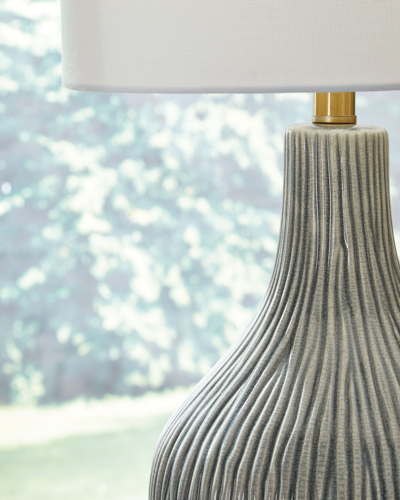 Gray ceramic lamp base with vertical ridges and gold collar under white shade