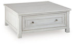 White coffee table with a smooth top and one long drawer with metal knobs.