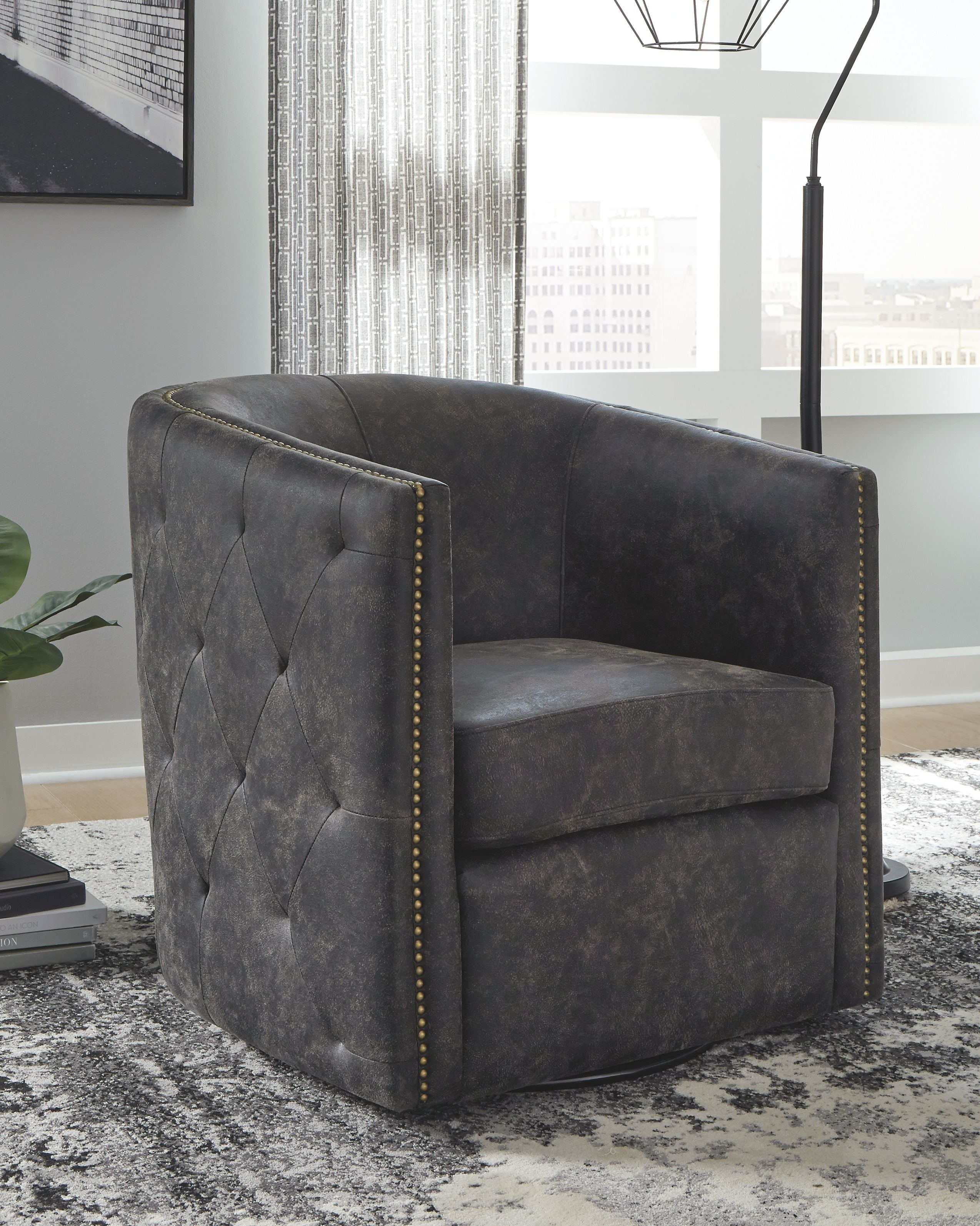 Swivel accent chair with dark upholstery, button-tufted back, and gold nailhead trim