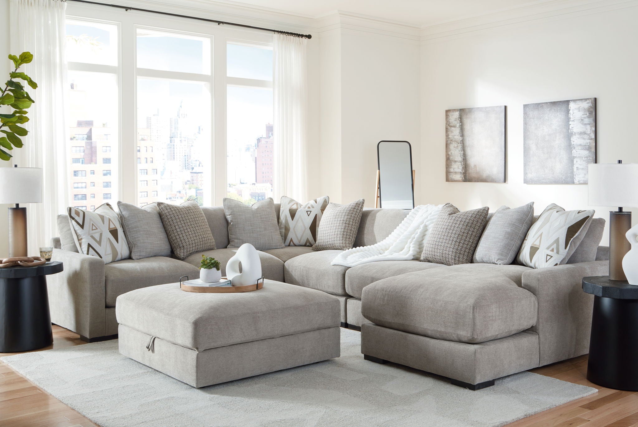 Gray sectional sofa with chaise corner and patterned throw pillows, styled with matching ottoman