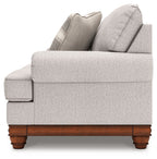 Upholstered loveseat side view with solid back, rolled arms, and wooden feet